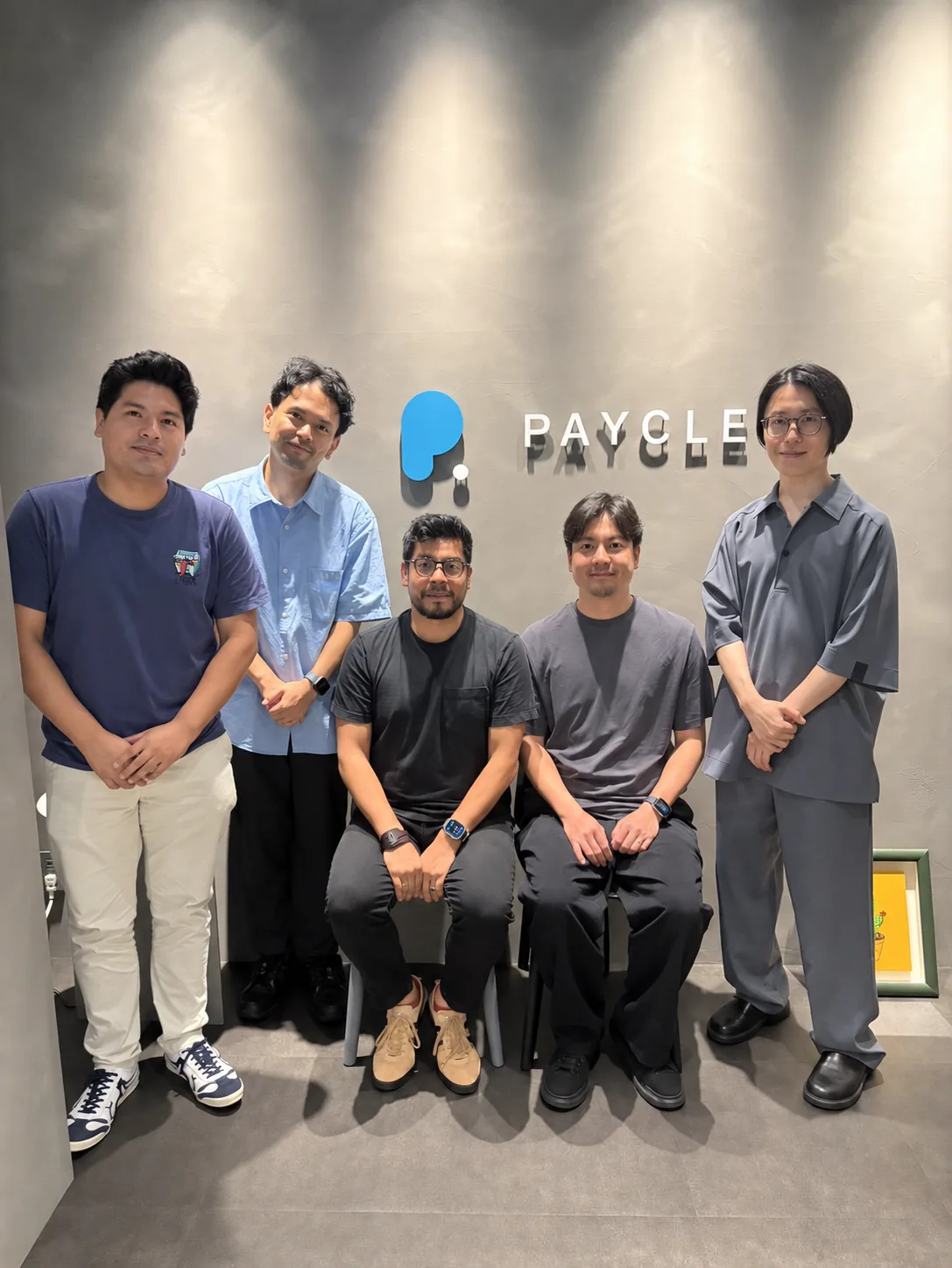 本社オフィスのPAYCLEロゴ前で、CTOファビアン・メザリナと本社メンバー5名が並んだ記念写真