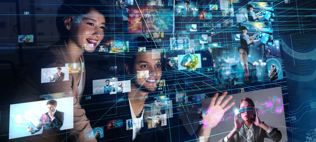 複数のデジタル映像が浮かぶインターフェースを前に、楽しそうに操作する男女。ホログラムやVRなどの未来的なテクノロジーが広がる空間で、情報や映像がネットワーク状に表示されるシーン。