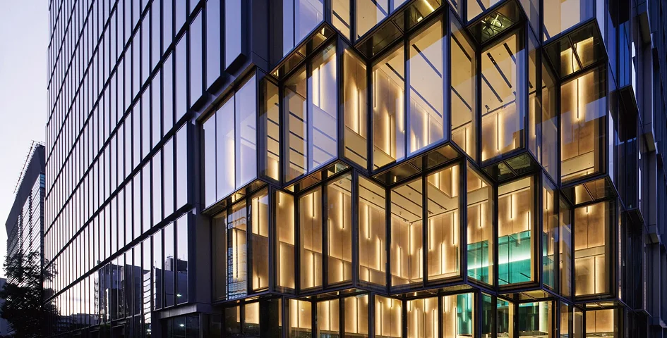 夕暮れ時にライトアップされた近代的なガラス張りの建物の外観