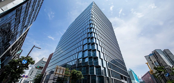 青空を反射するガラス張りの高層オフィスビル