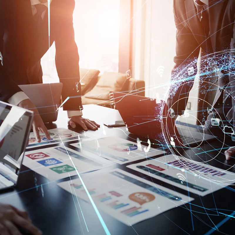 ビジネスパーソンが資料やグラフを囲んで議論する会議風景と、右側に重なるように描かれた地球とネットワークが示すグローバル戦略のイメージ