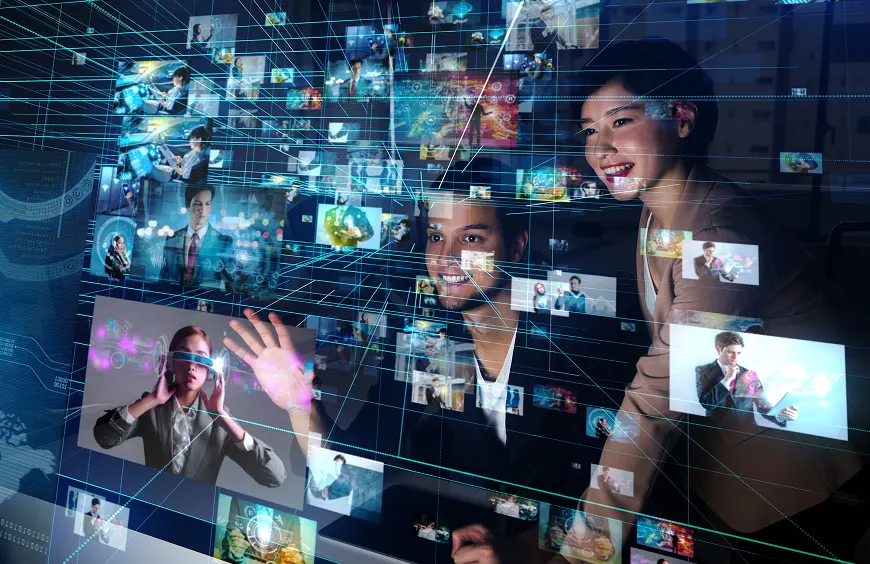 複数のデジタル映像が浮かぶインターフェースを前に、楽しそうに操作する男女。ホログラムやVRなどの未来的なテクノロジーが広がる空間で、情報や映像がネットワーク状に表示されるシーン。