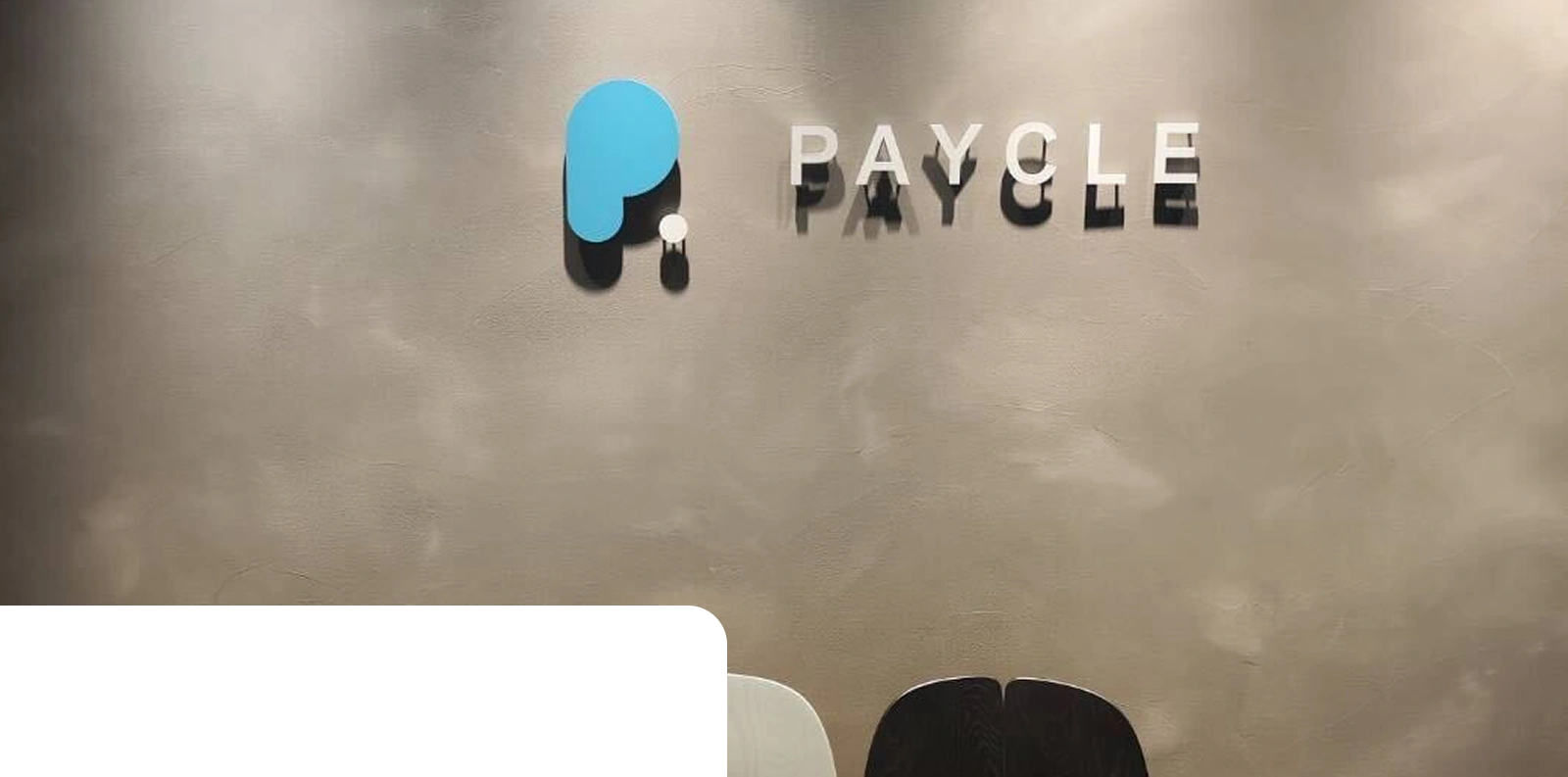 グレーの壁面に設置された、PAYCLEの立体ロゴと社名サイン