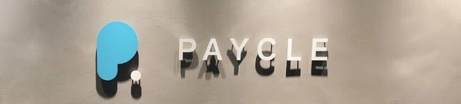 グレーの壁面に設置された、PAYCLEの立体ロゴと社名サイン